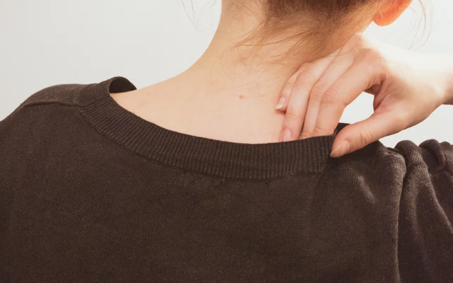 普段着の人が首の後ろに手を当てている後ろ姿（イメージ）